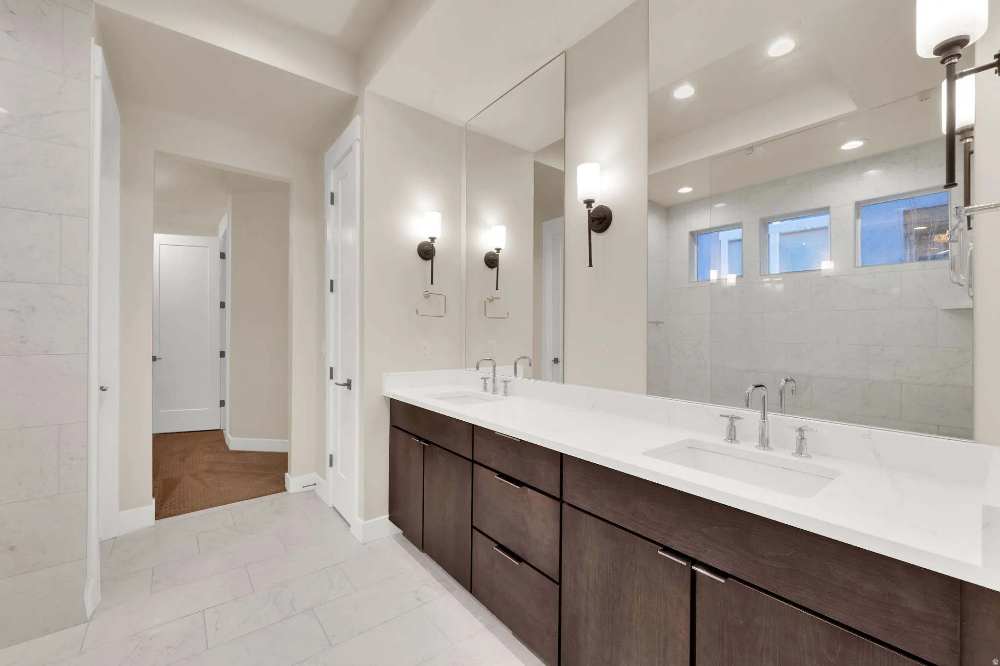 Bathroom with double vanity and light marble finish floors