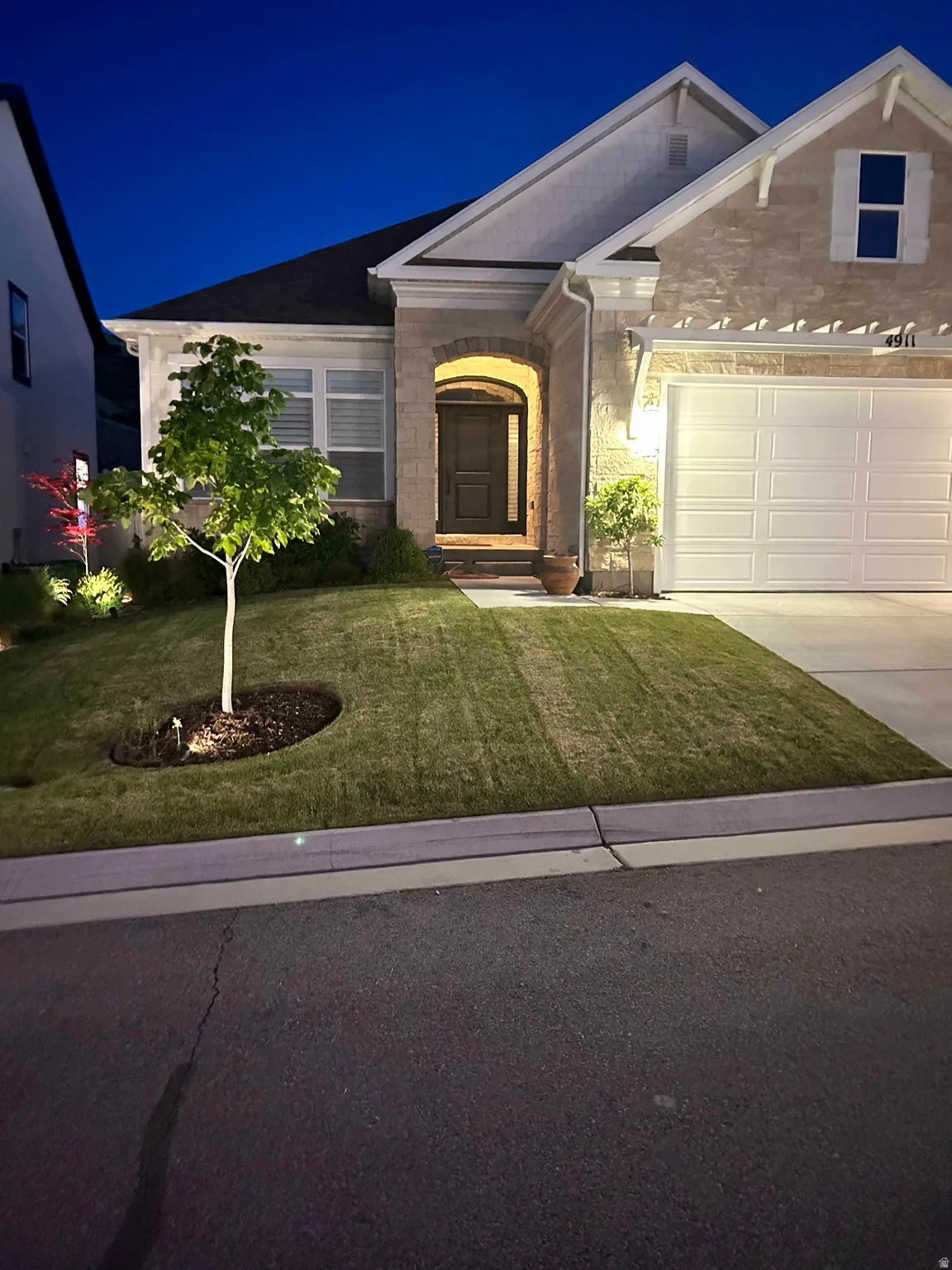 View of front of property with a lawn, stone siding, and driveway