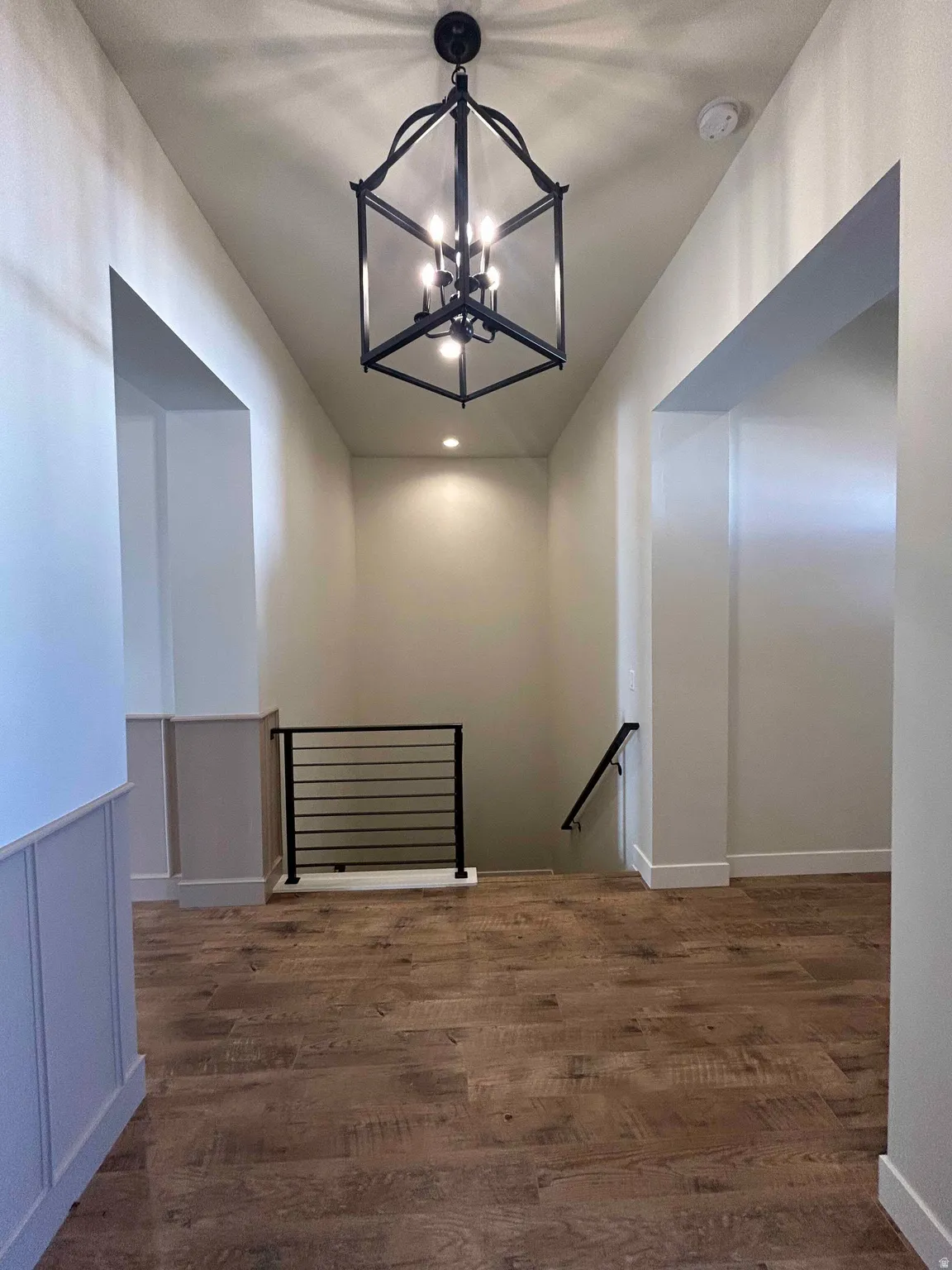 Hall featuring an upstairs landing, a chandelier, and dark wood-style flooring