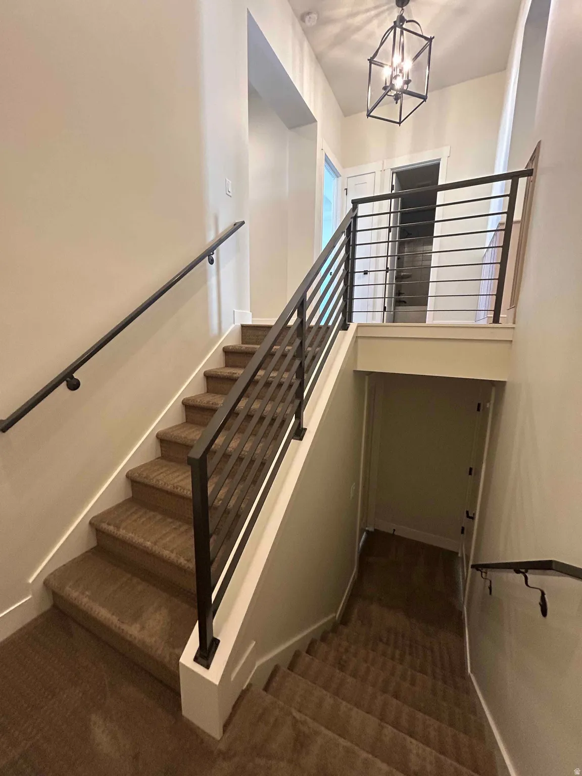 Staircase with carpet and suspended lighting