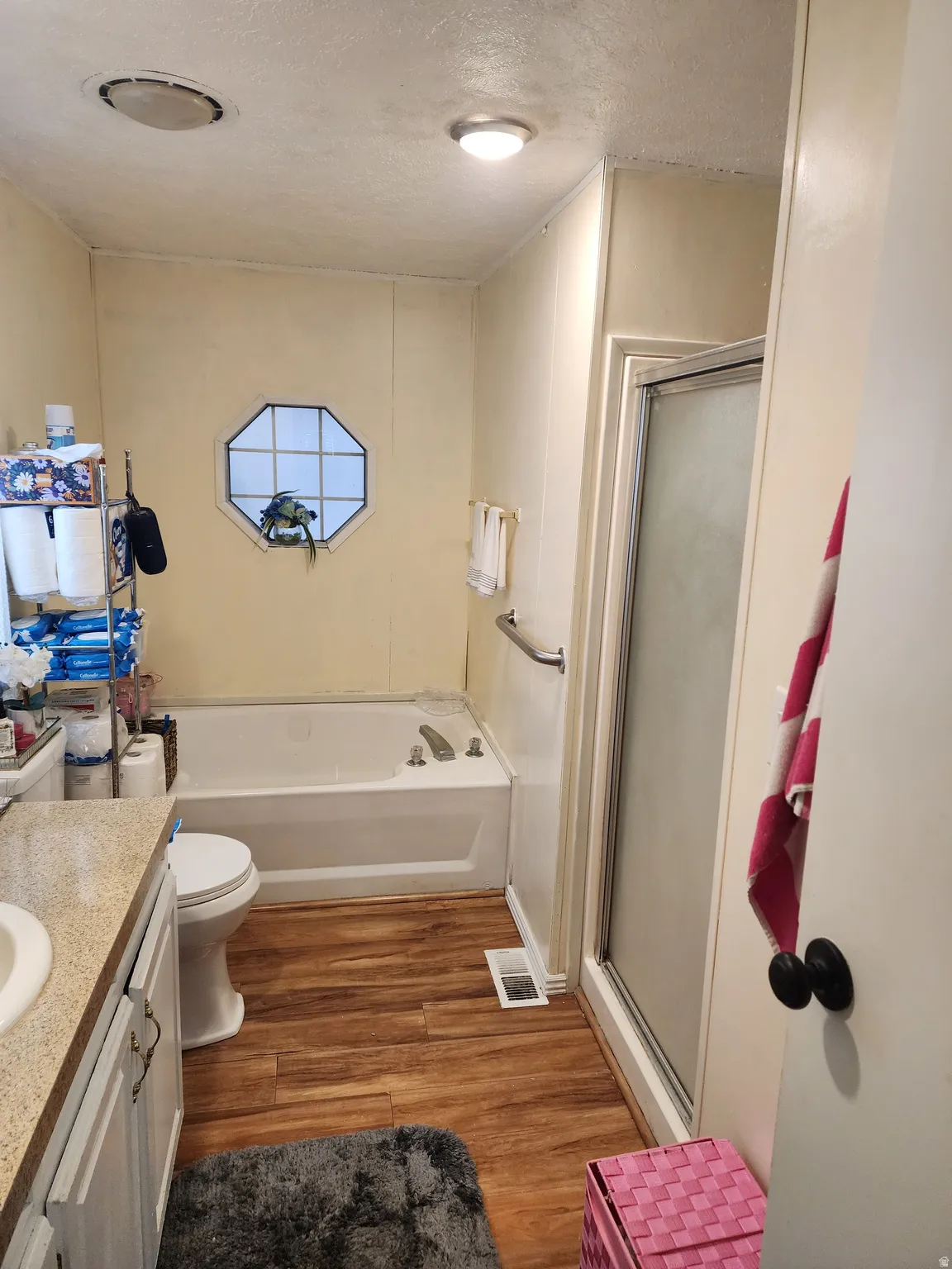 Bathroom featuring vanity, light wood-style flooring, a textured ceiling, a shower stall, and a bath
