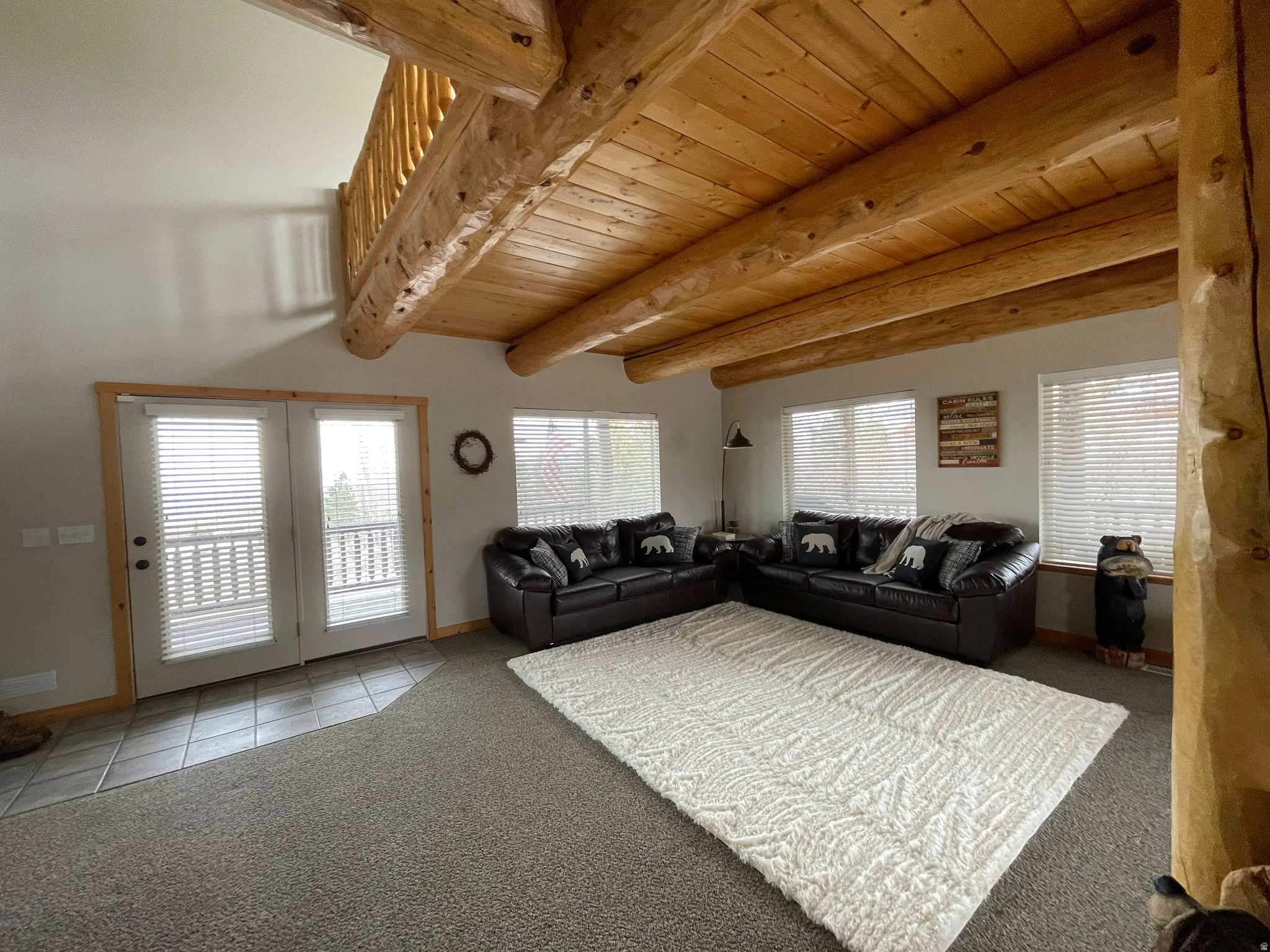 Living room with light carpet, a wood ceiling with exposed beams, and light tile patterned floors