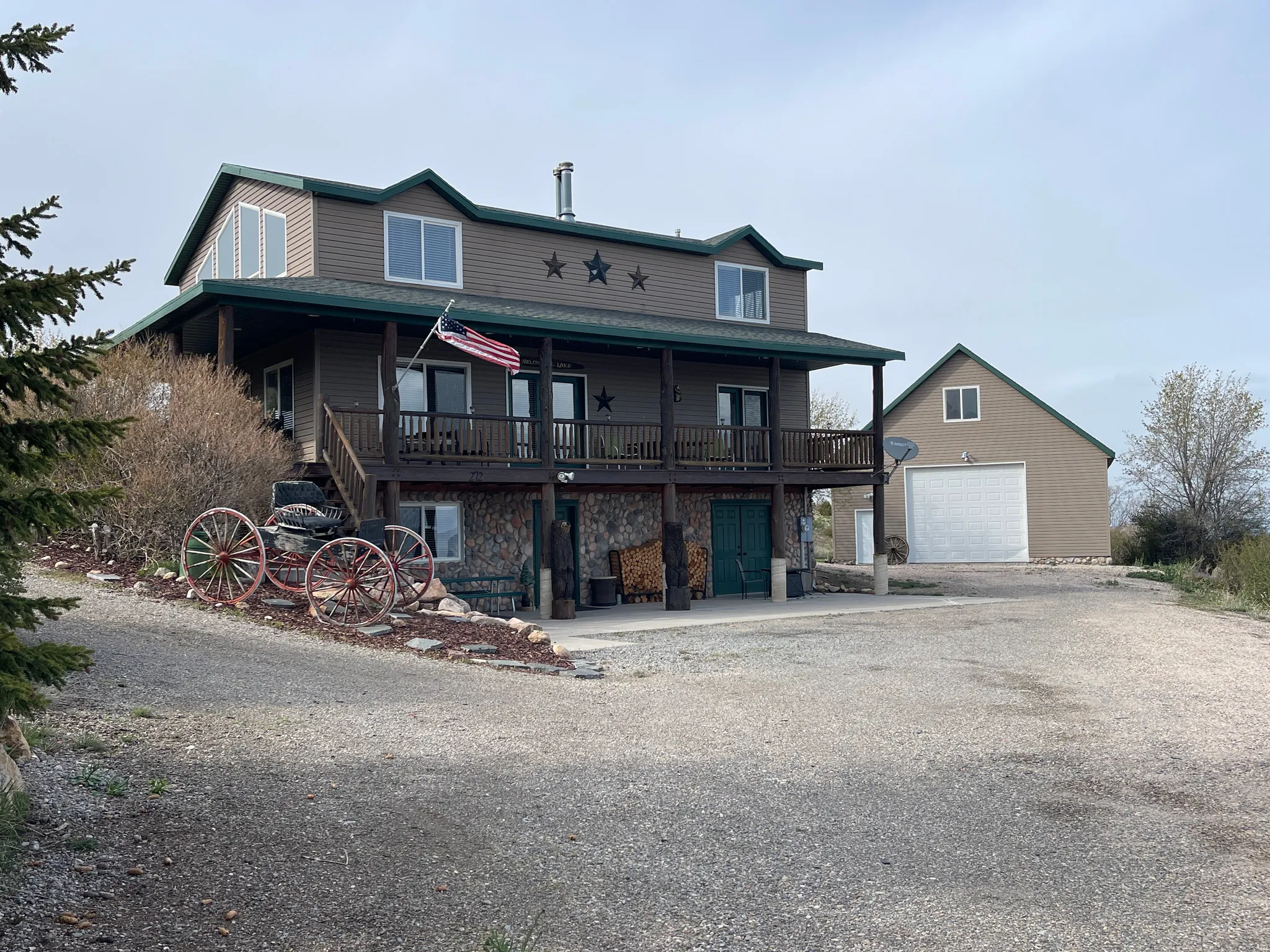 View of front of property featuring covered porch, an outbuilding, gravel driveway, and stone siding