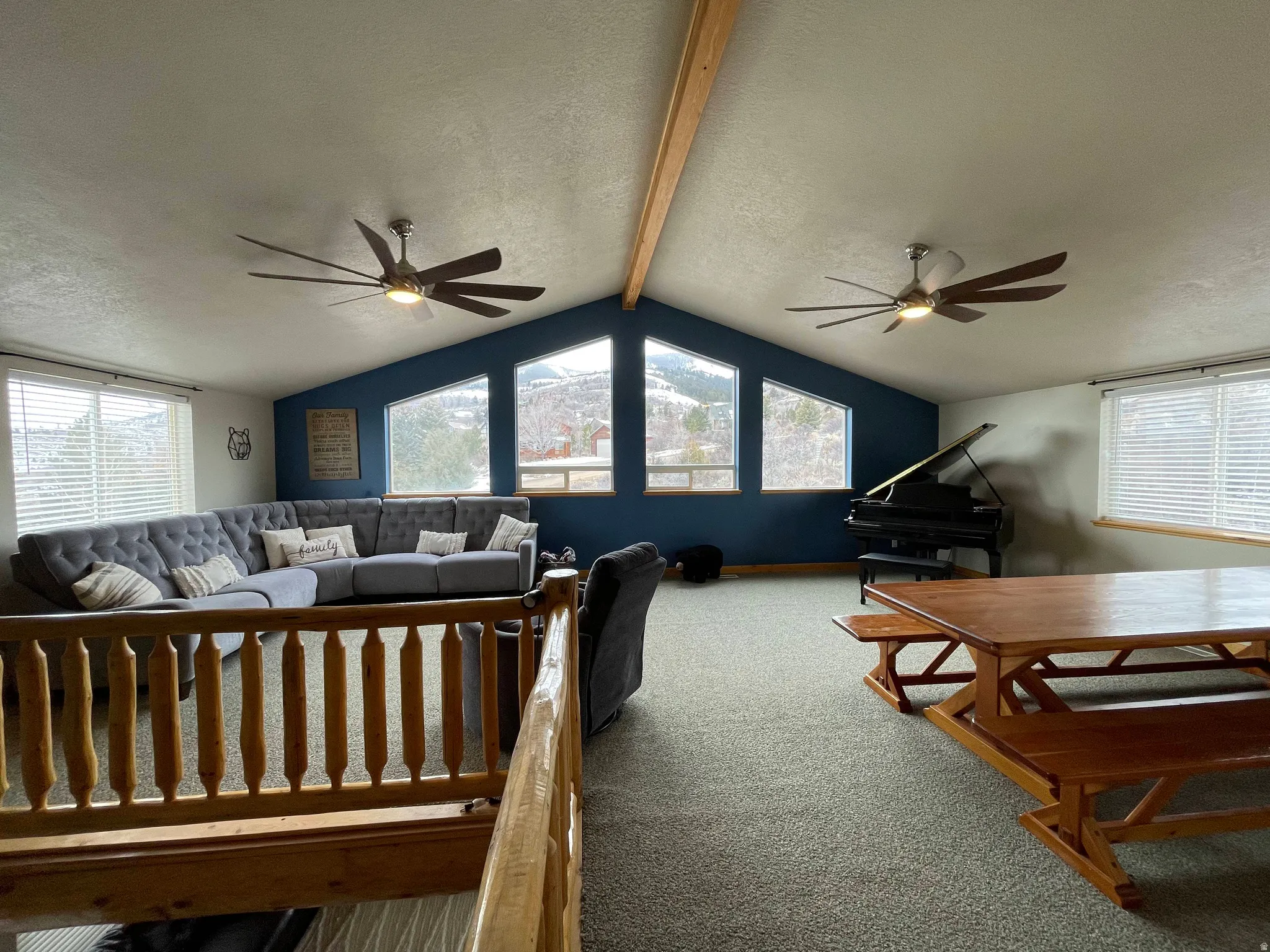 Living room featuring a textured ceiling, a ceiling fan, beamed ceiling, and carpet flooring