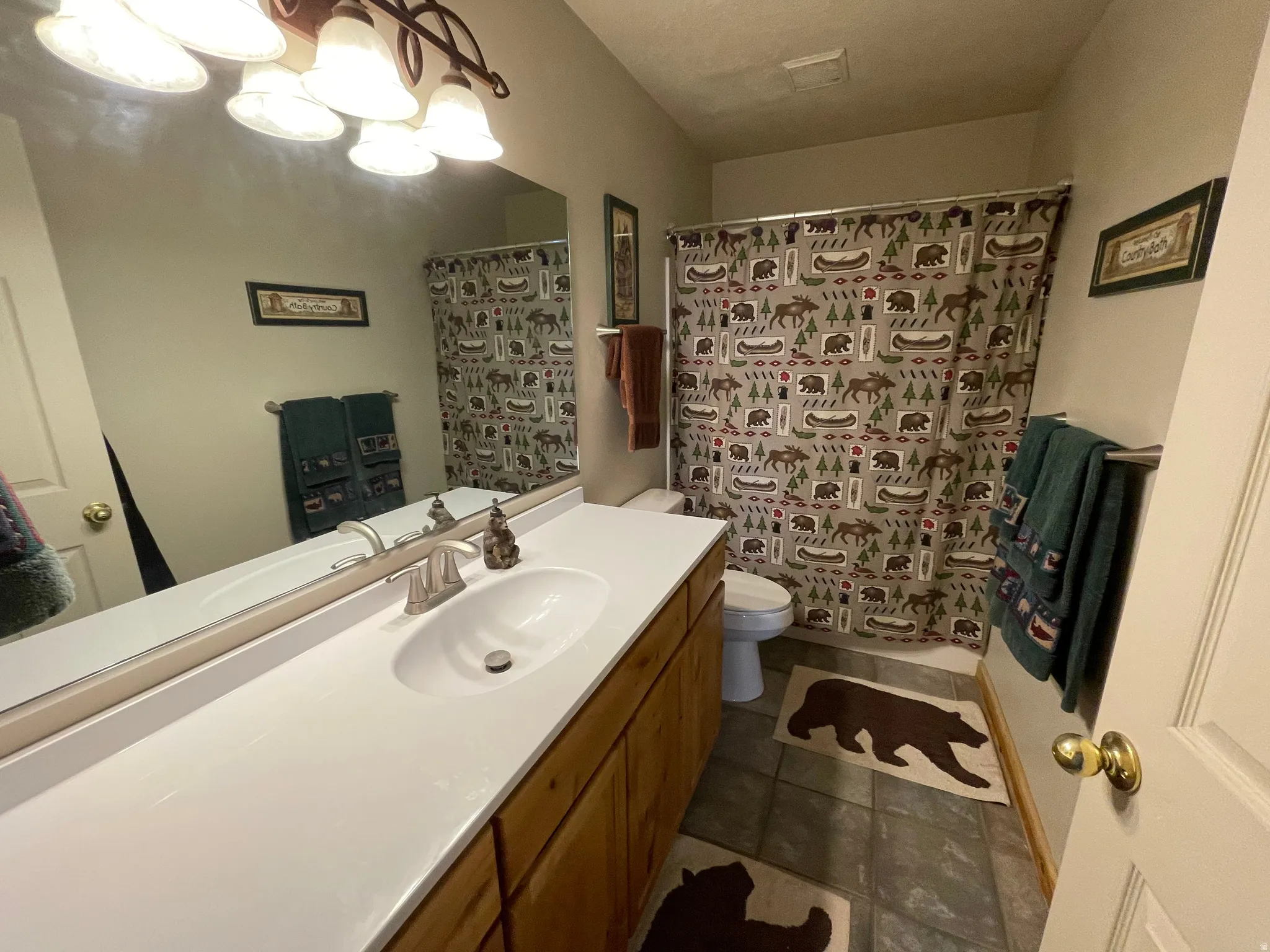 Full bath with vanity, curtained shower, and dark tile patterned flooring