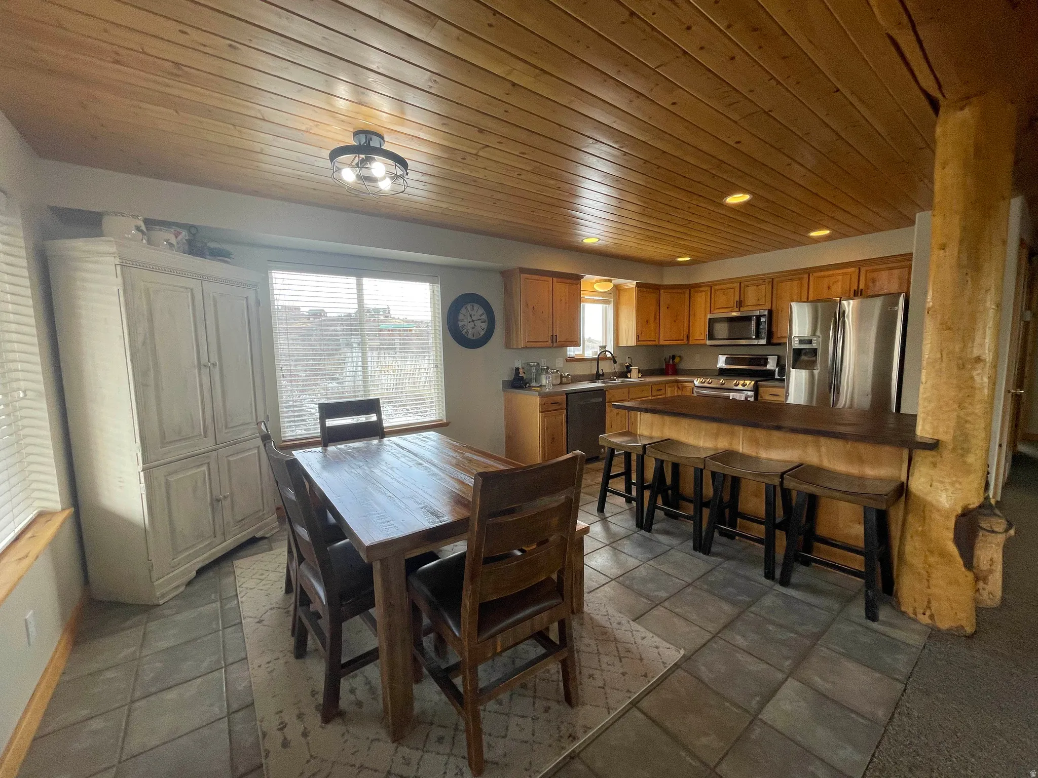 Dining space with wooden ceiling and dark stone finish floors