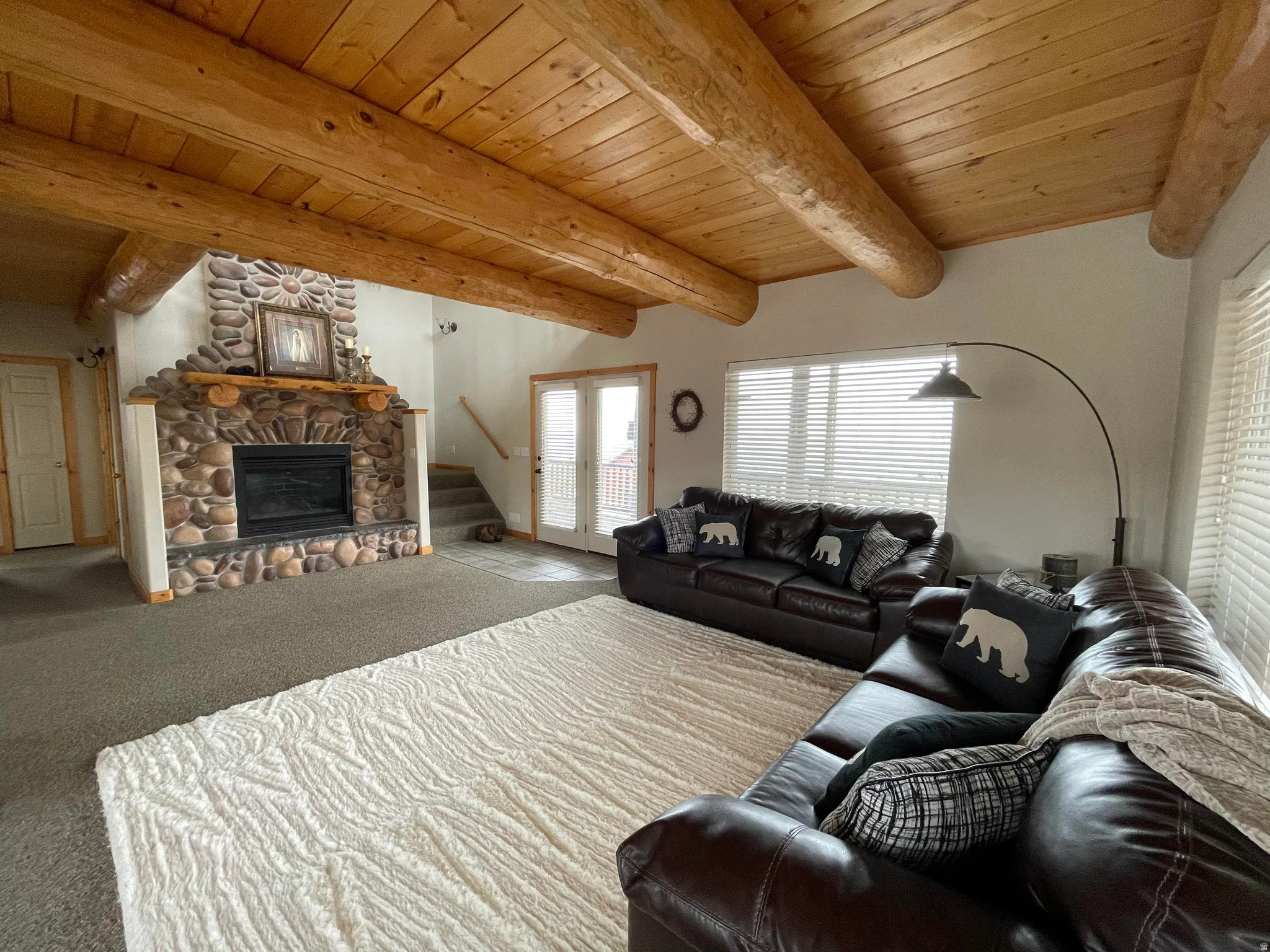 Living room with a wooden ceiling with exposed beams, a fireplace, and carpet