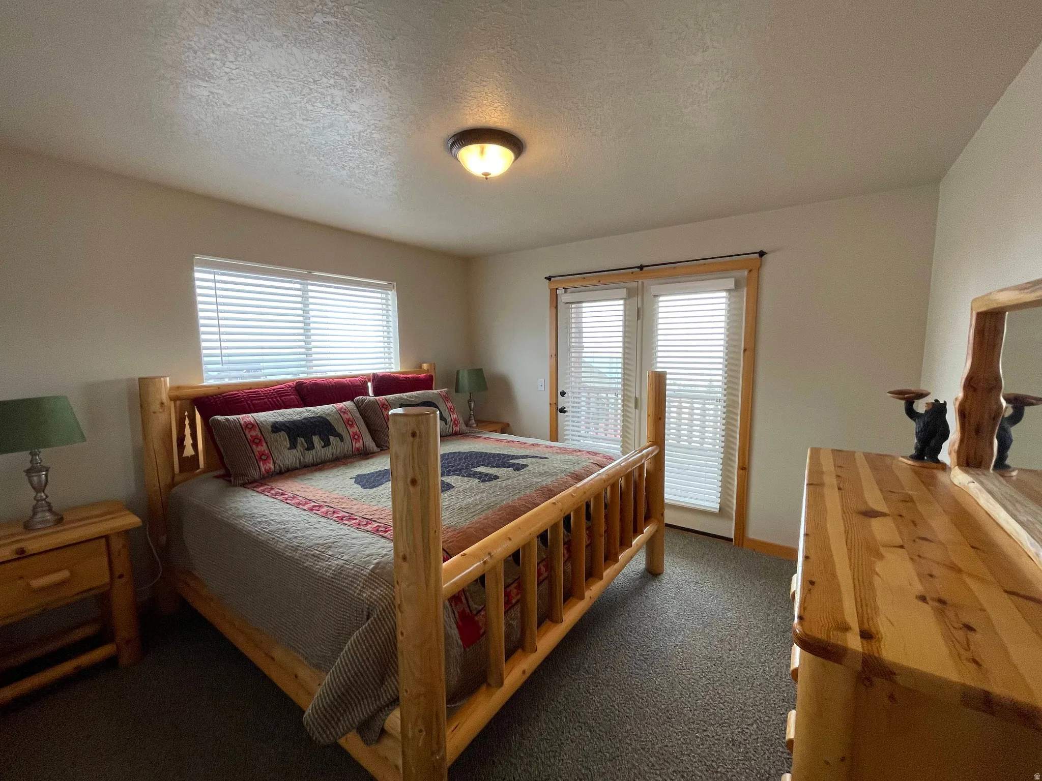 Bedroom with a textured ceiling, dark carpet, and multiple windows
