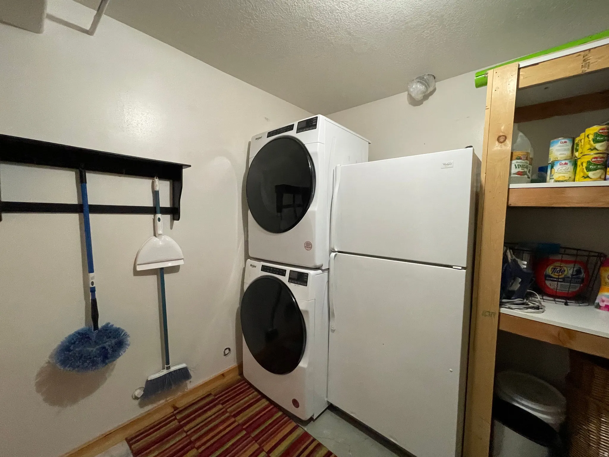 Laundry area featuring stacked washing machine and dryer and a textured ceiling