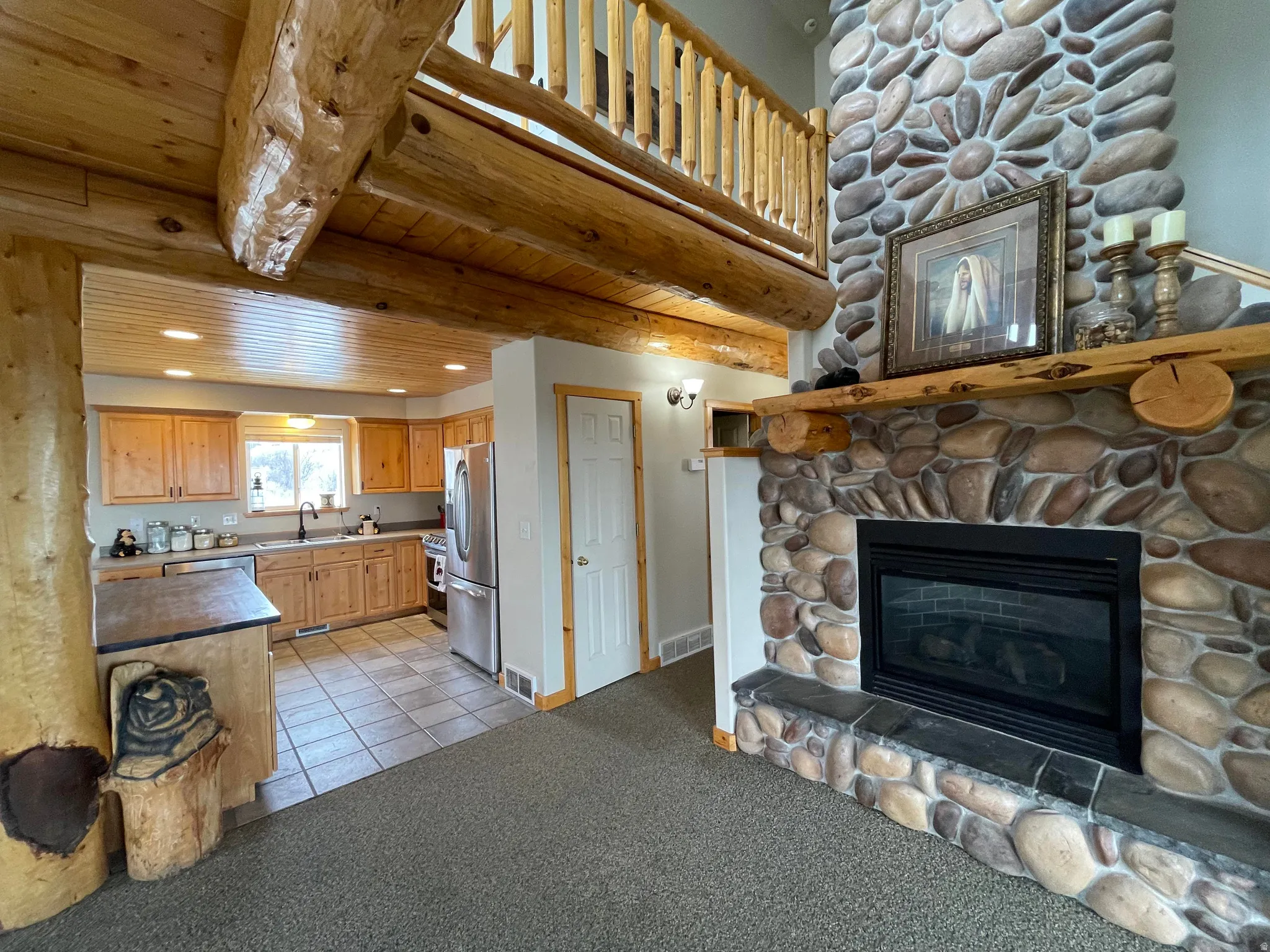 Kitchen with light carpet, stainless steel appliances, a fireplace, light tile patterned floors, and recessed lighting