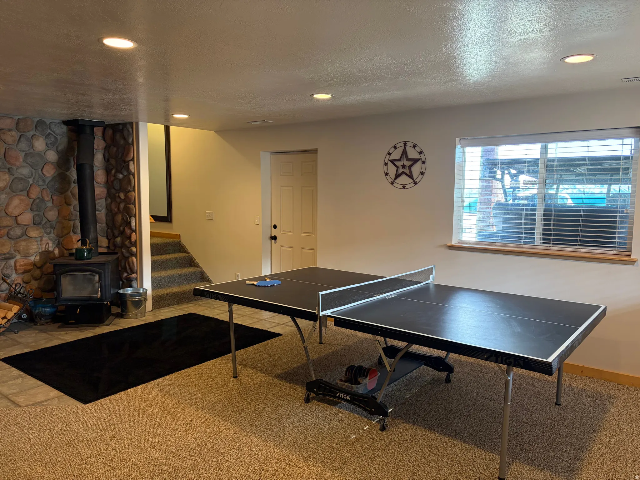 Recreation room featuring carpet floors, a wood stove, recessed lighting, and a textured ceiling