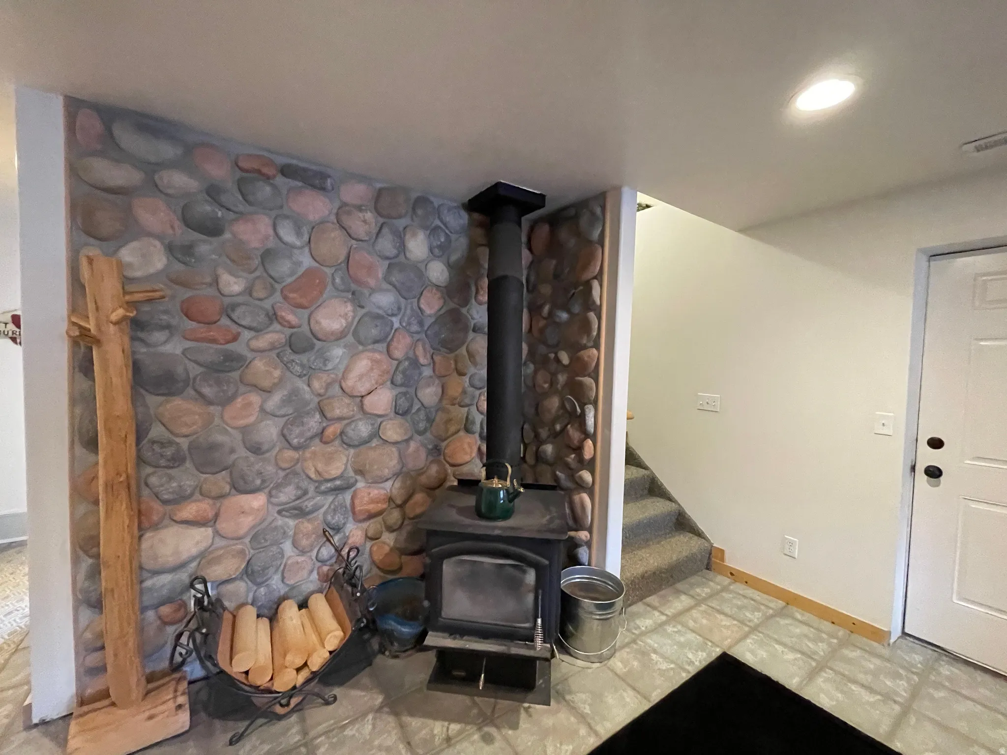 Detailed view of tile patterned floors, recessed lighting, and a wood stove