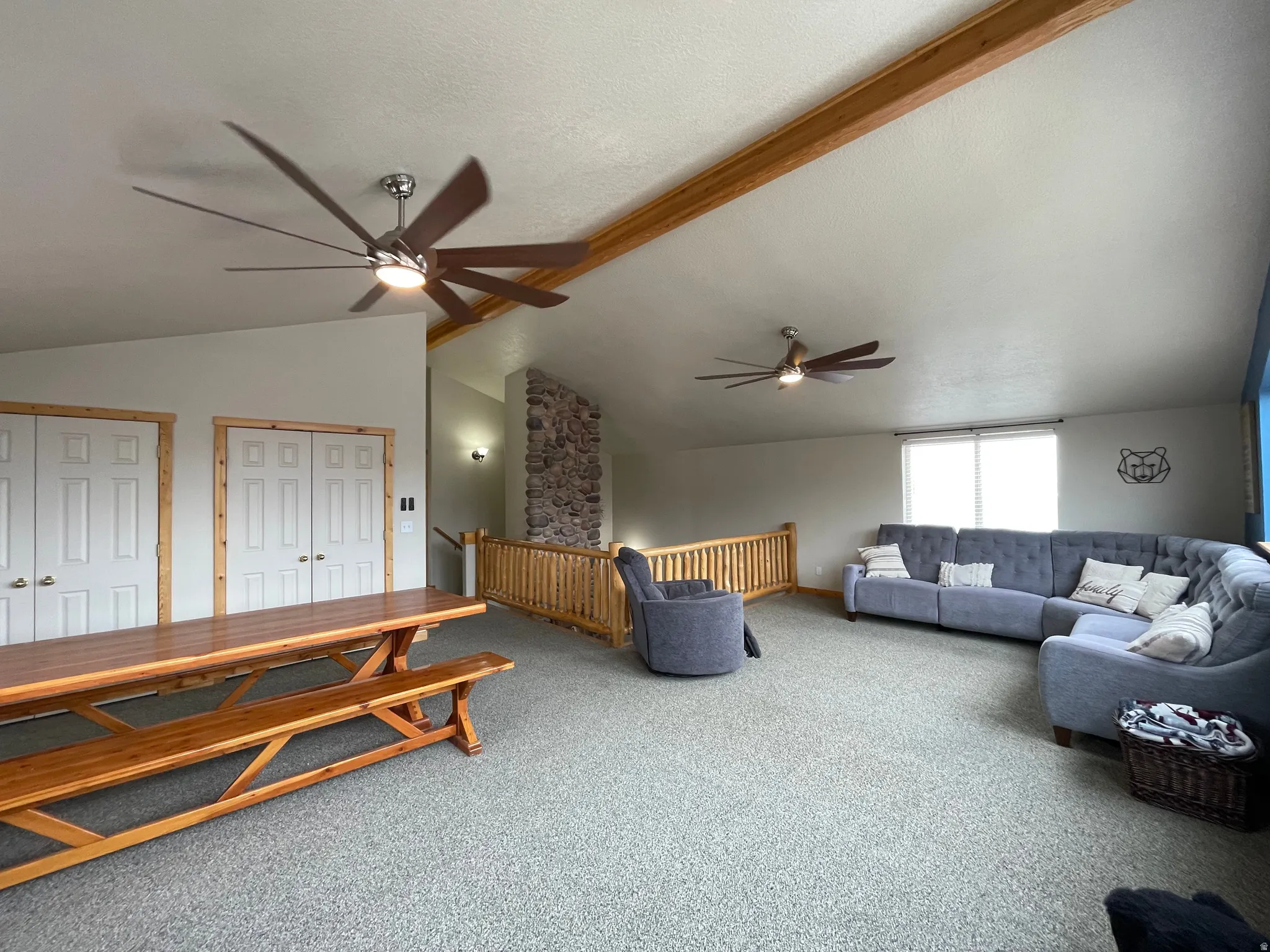 Living room featuring a ceiling fan, carpet flooring, and lofted ceiling with beams