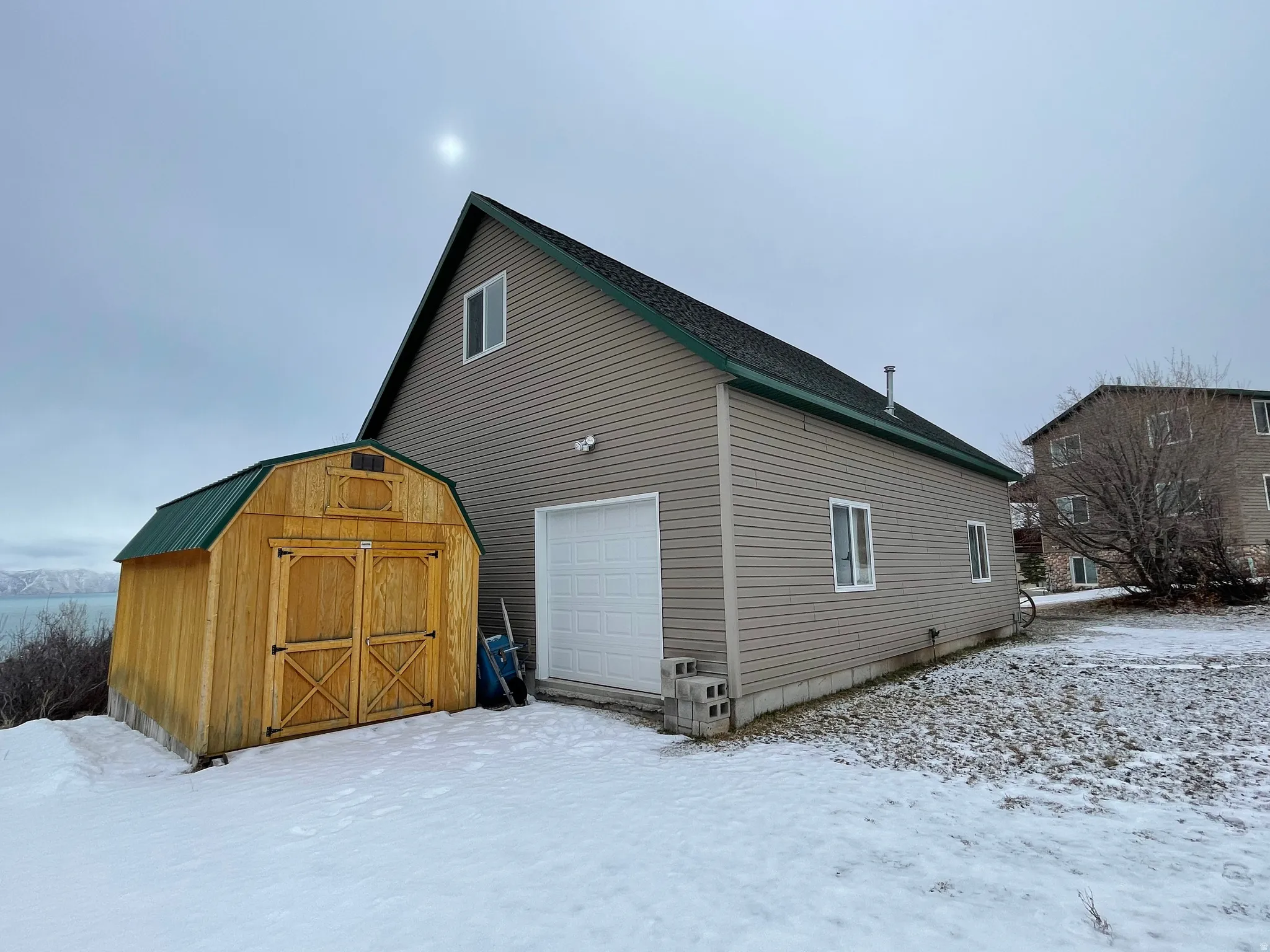 Snow covered garage with a shed and a garage