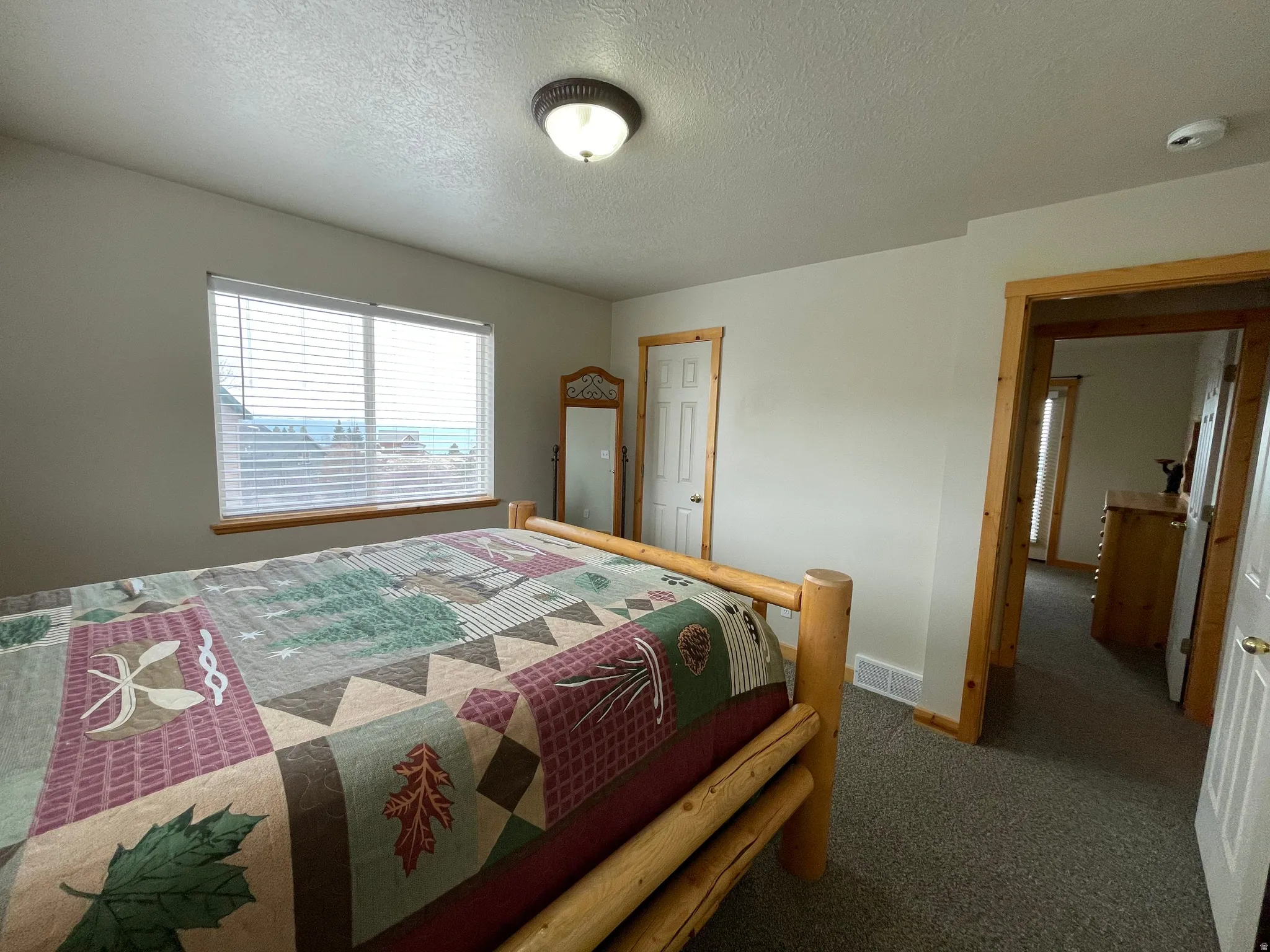 Bedroom featuring a textured ceiling and dark colored carpet