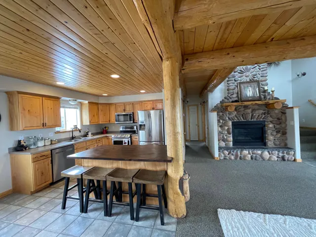 Kitchen featuring stainless steel appliances, recessed lighting, a stone fireplace, open floor plan, and wood ceiling