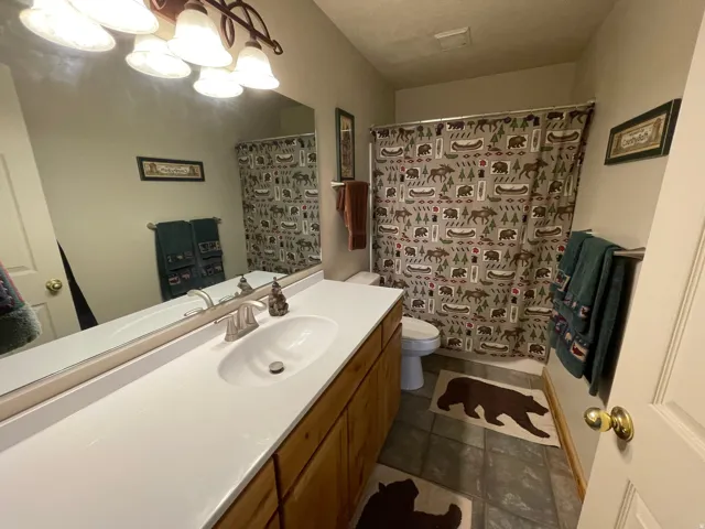 Full bath with vanity, curtained shower, and dark tile patterned flooring