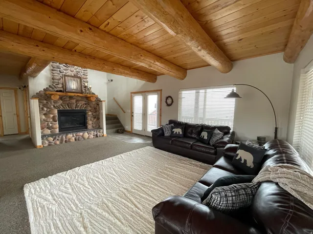 Living room with a wooden ceiling with exposed beams, a fireplace, and carpet