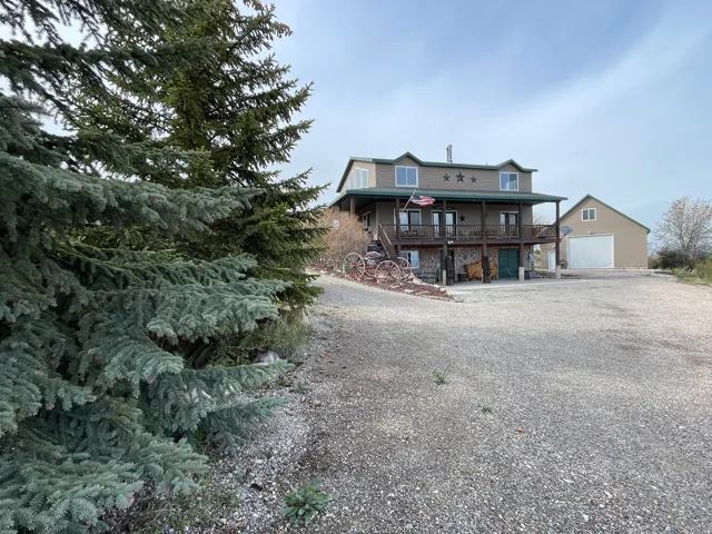 View of front facade featuring a garage, gravel driveway, and covered porch