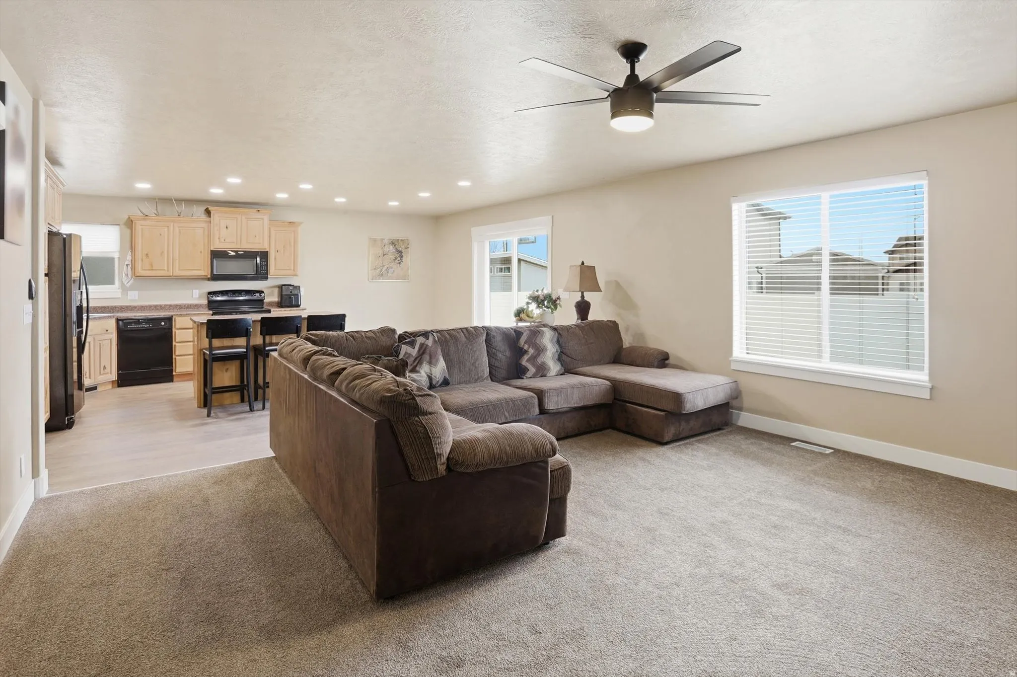 Living room featuring light carpet, recessed lighting, ceiling fan, and a textured ceiling