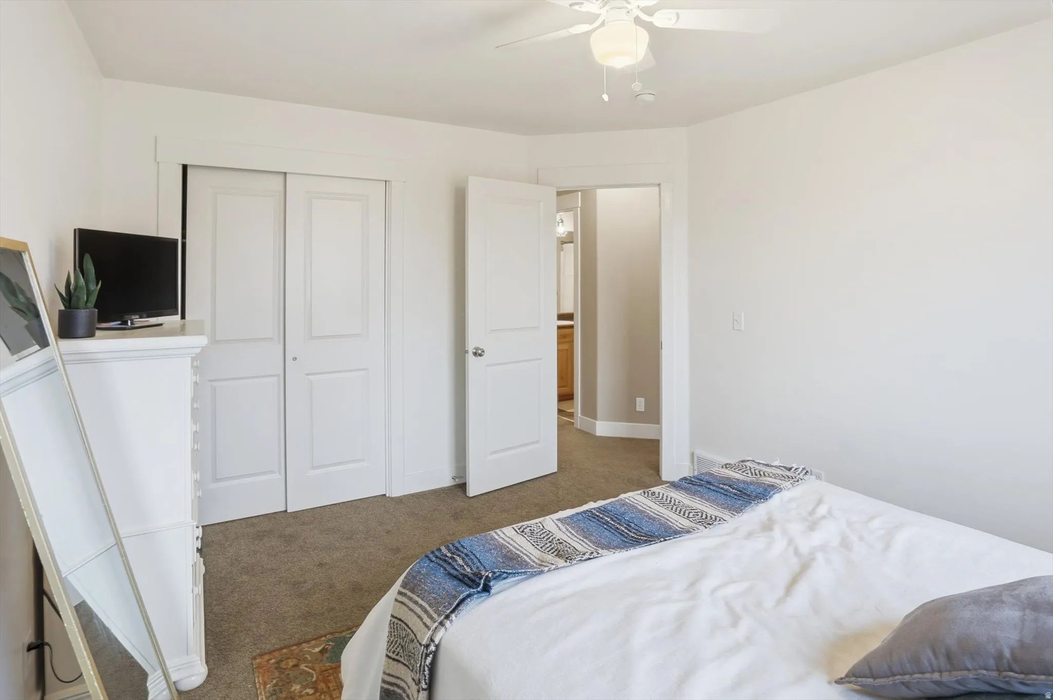 Bedroom featuring light colored carpet, a closet, and a ceiling fan
