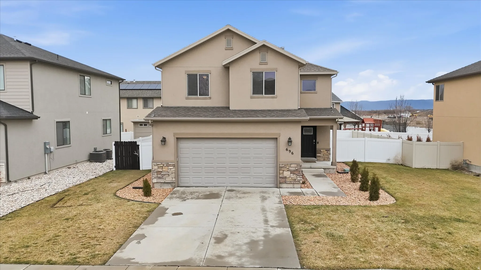 Traditional home with an attached garage, driveway, stone siding, and stucco siding