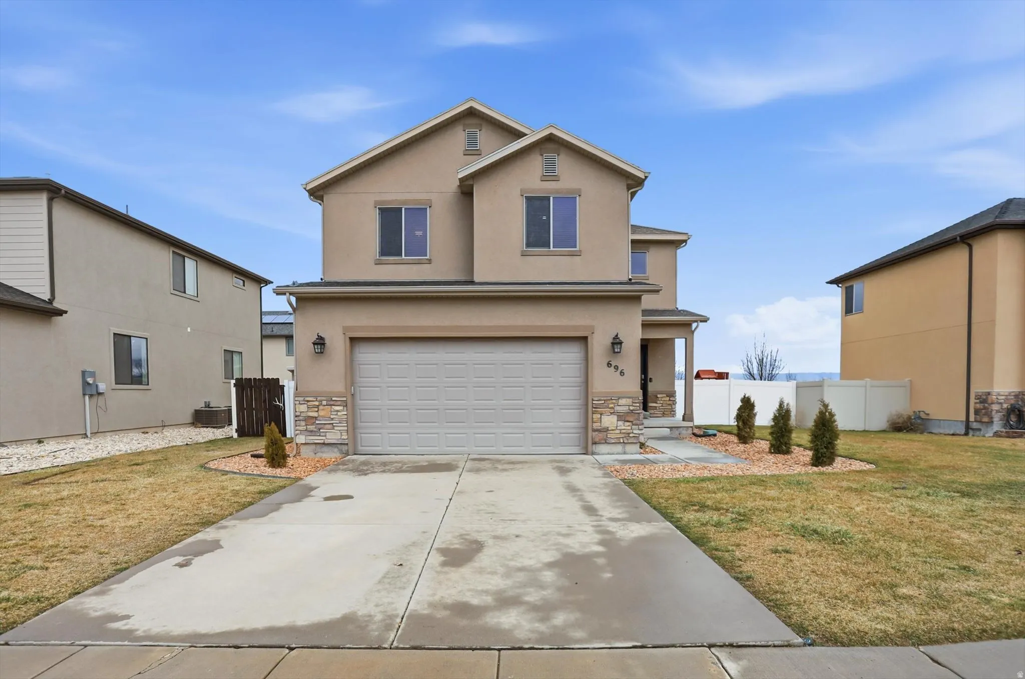 Traditional home with stone siding, an attached garage, concrete driveway, and stucco siding