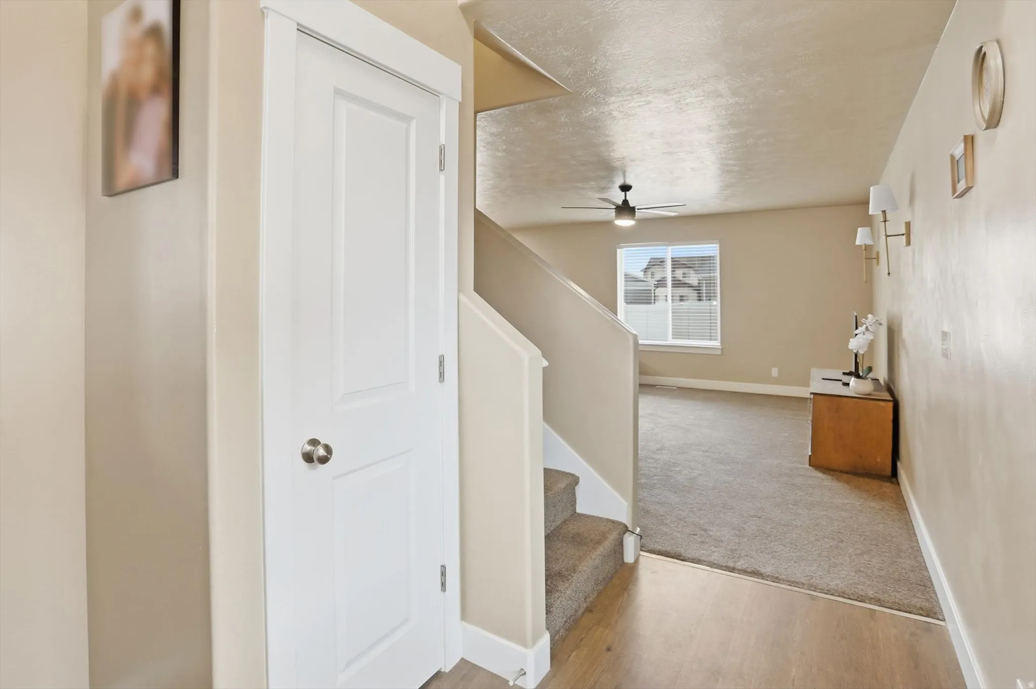 Stairway with a ceiling fan, a textured ceiling, wood finished floors, and carpet flooring