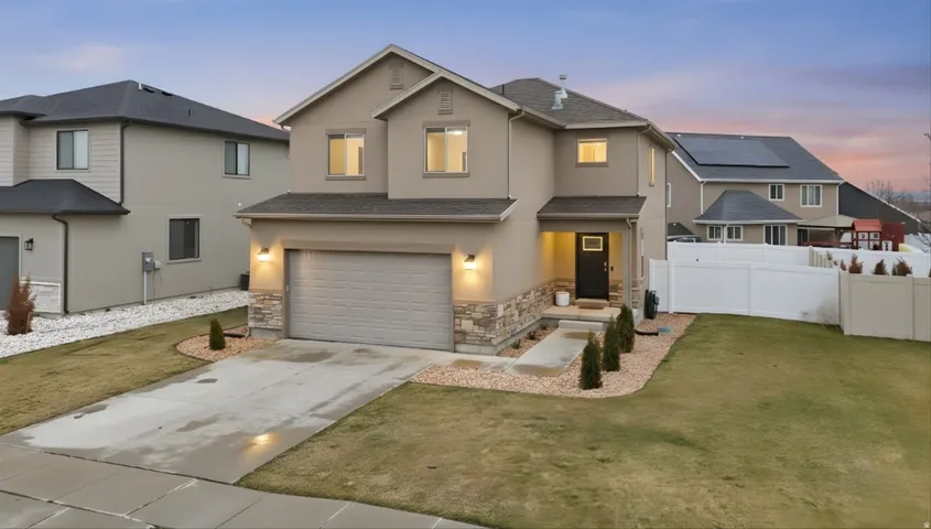 Traditional-style house featuring an attached garage, stucco siding, driveway, stone siding, and roof with shingles