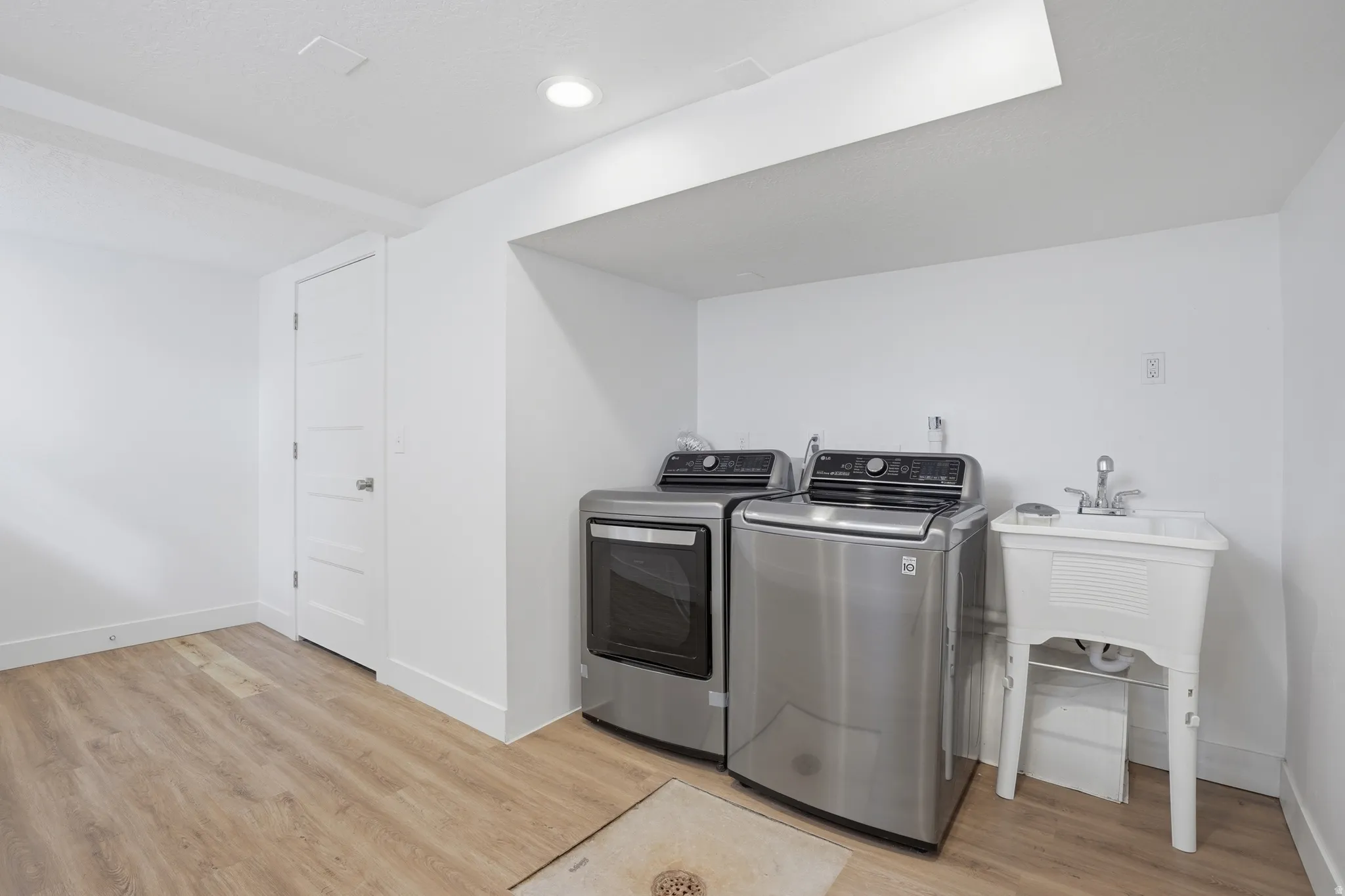 Downstairs Laundry area with light wood-style flooring and washer and dryer