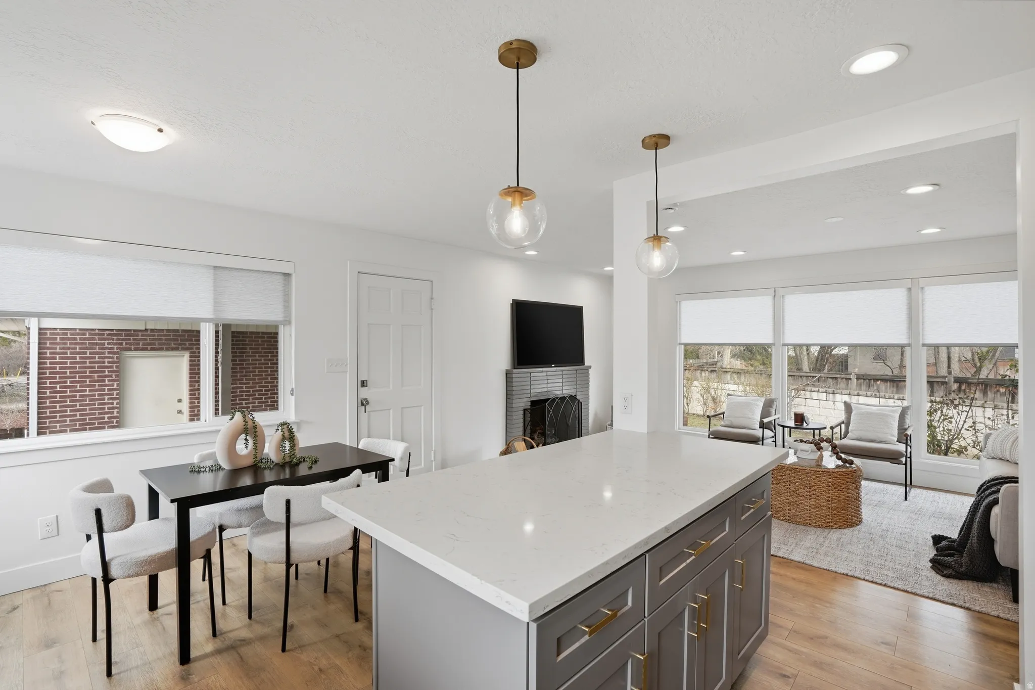 Kitchen with a kitchen island, decorative light fixtures, light wood finished floors, and a fireplace