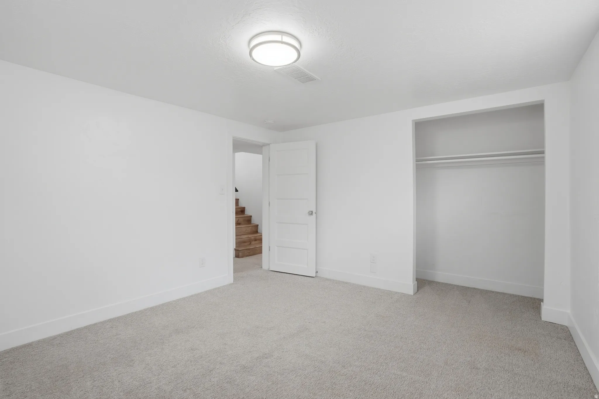 Basement bedroom with light colored carpet and a closet