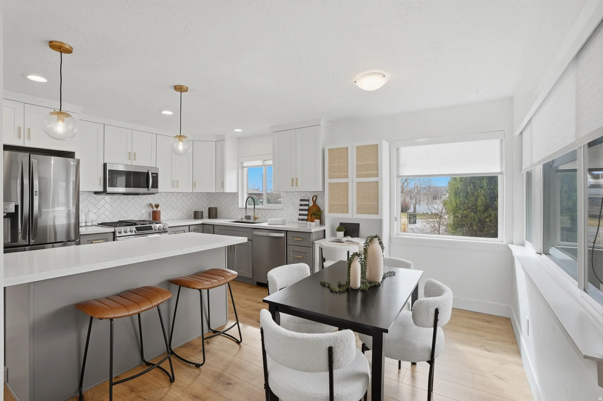 Kitchen featuring stainless steel appliances, light wood-style floors, dual tone cabinetry, decorative backsplash, and a breakfast bar