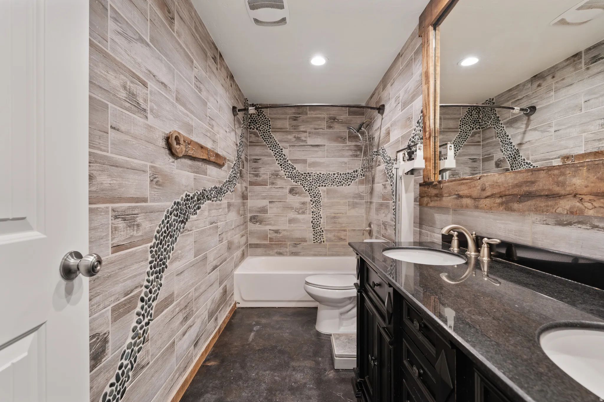 Bathroom featuring double vanity, bathtub / shower combination, concrete floors, and recessed lighting