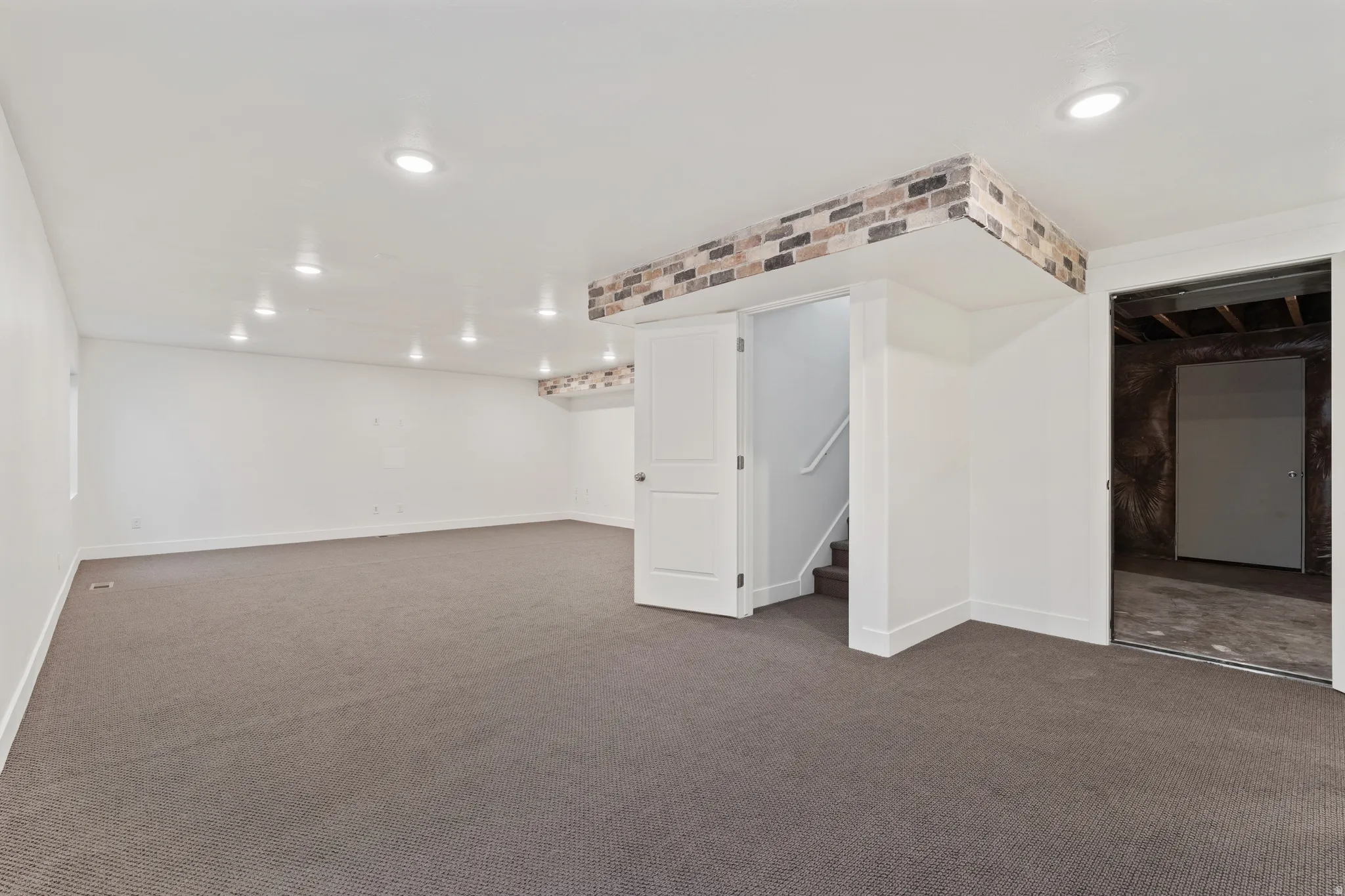 Finished below grade area with dark colored carpet and recessed lighting