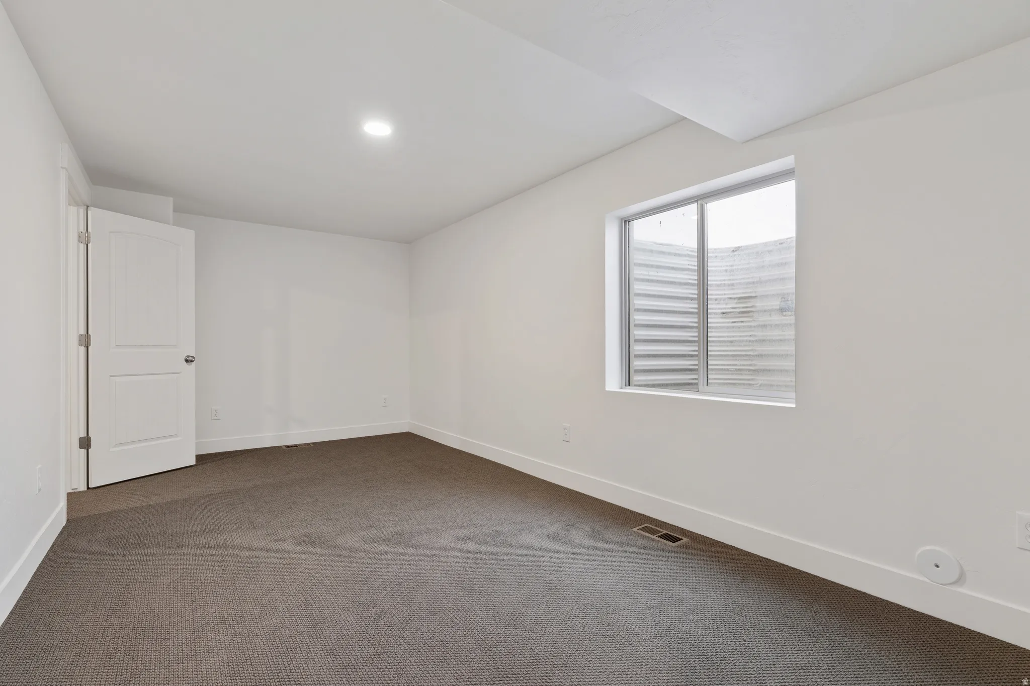 Empty room featuring dark colored carpet and recessed lighting