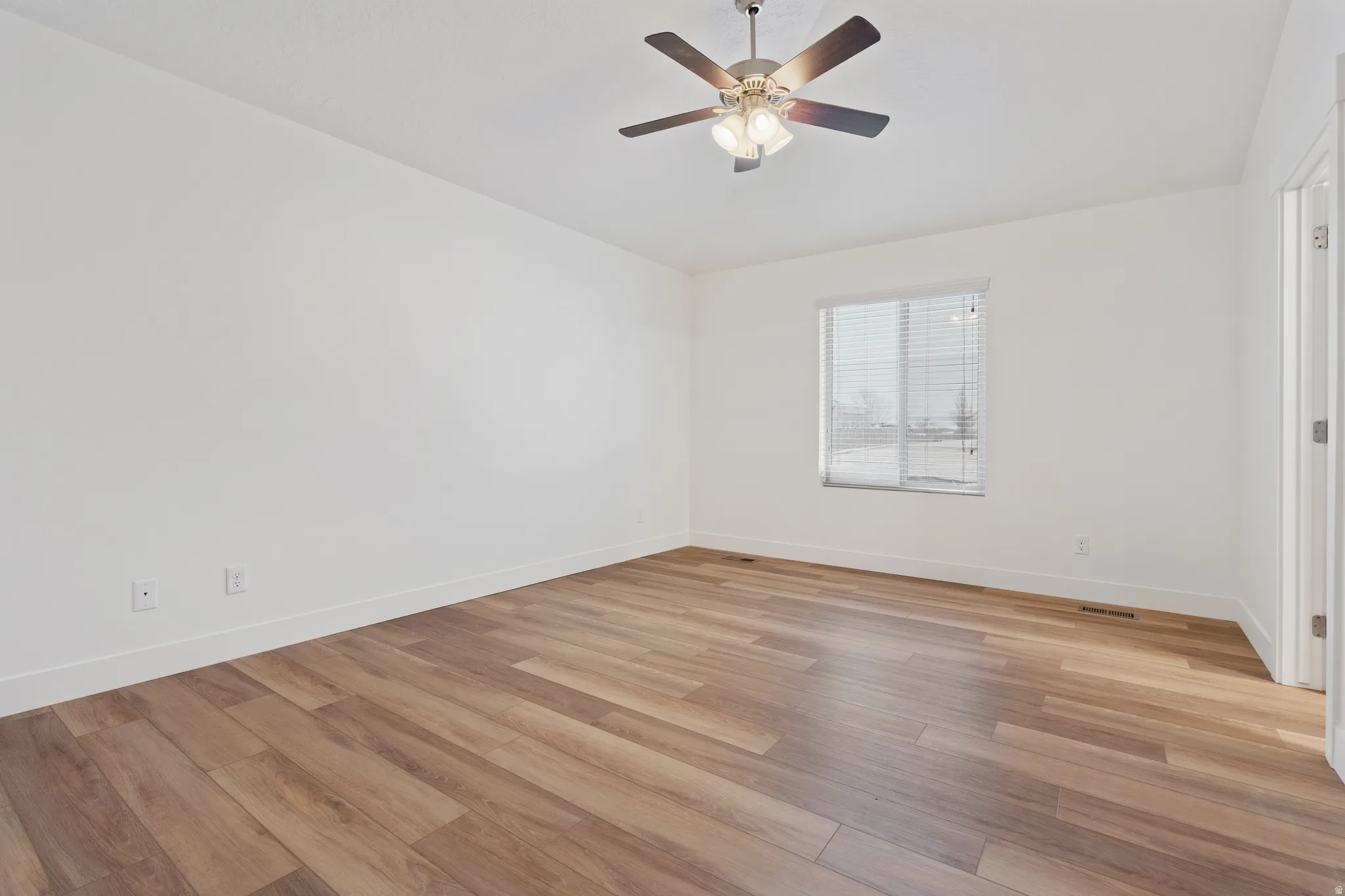 Empty room with light wood finished floors and a ceiling fan
