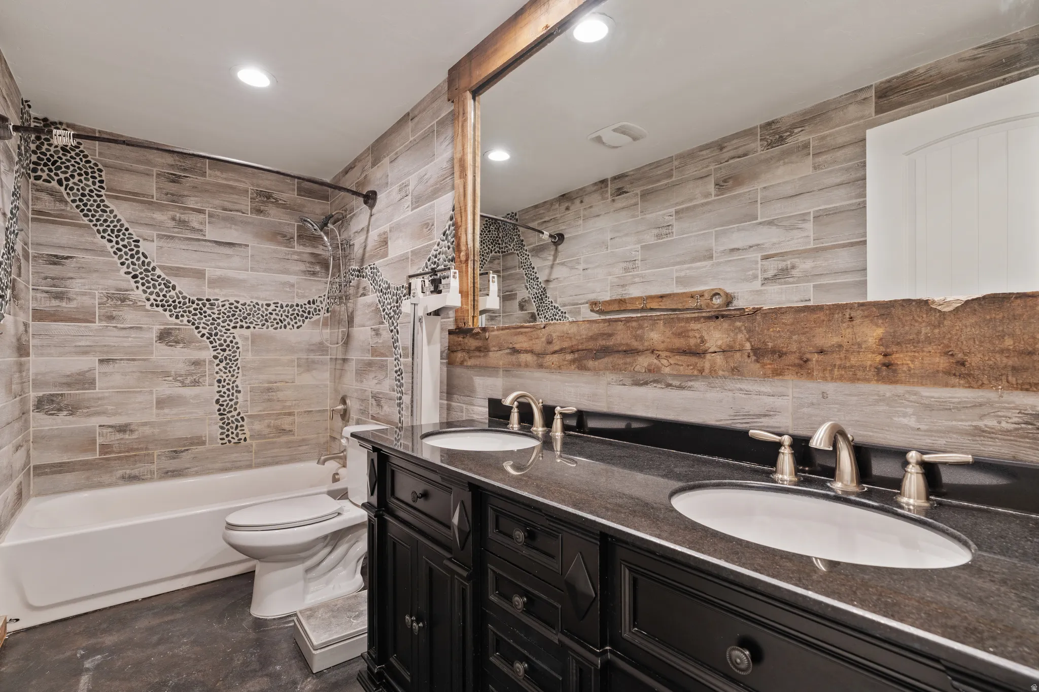 Full bathroom with double vanity, tile walls, shower / washtub combination, and recessed lighting