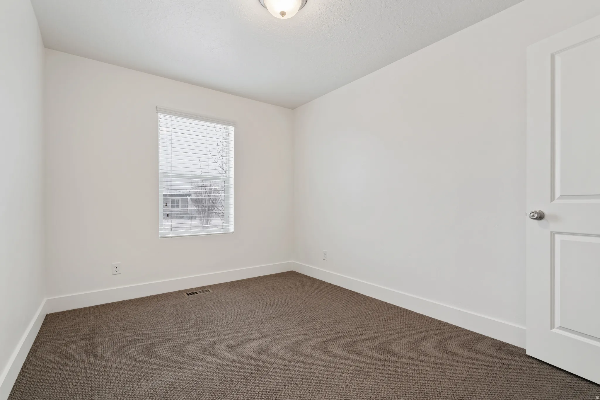 Empty room with baseboards and dark colored carpet