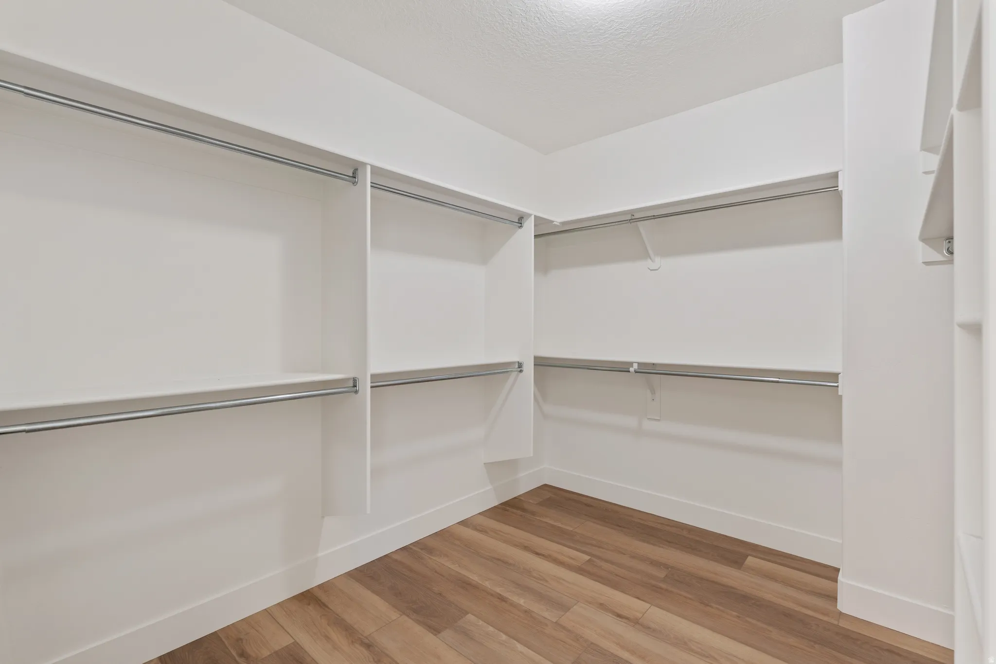 Walk in closet with light wood-type flooring
