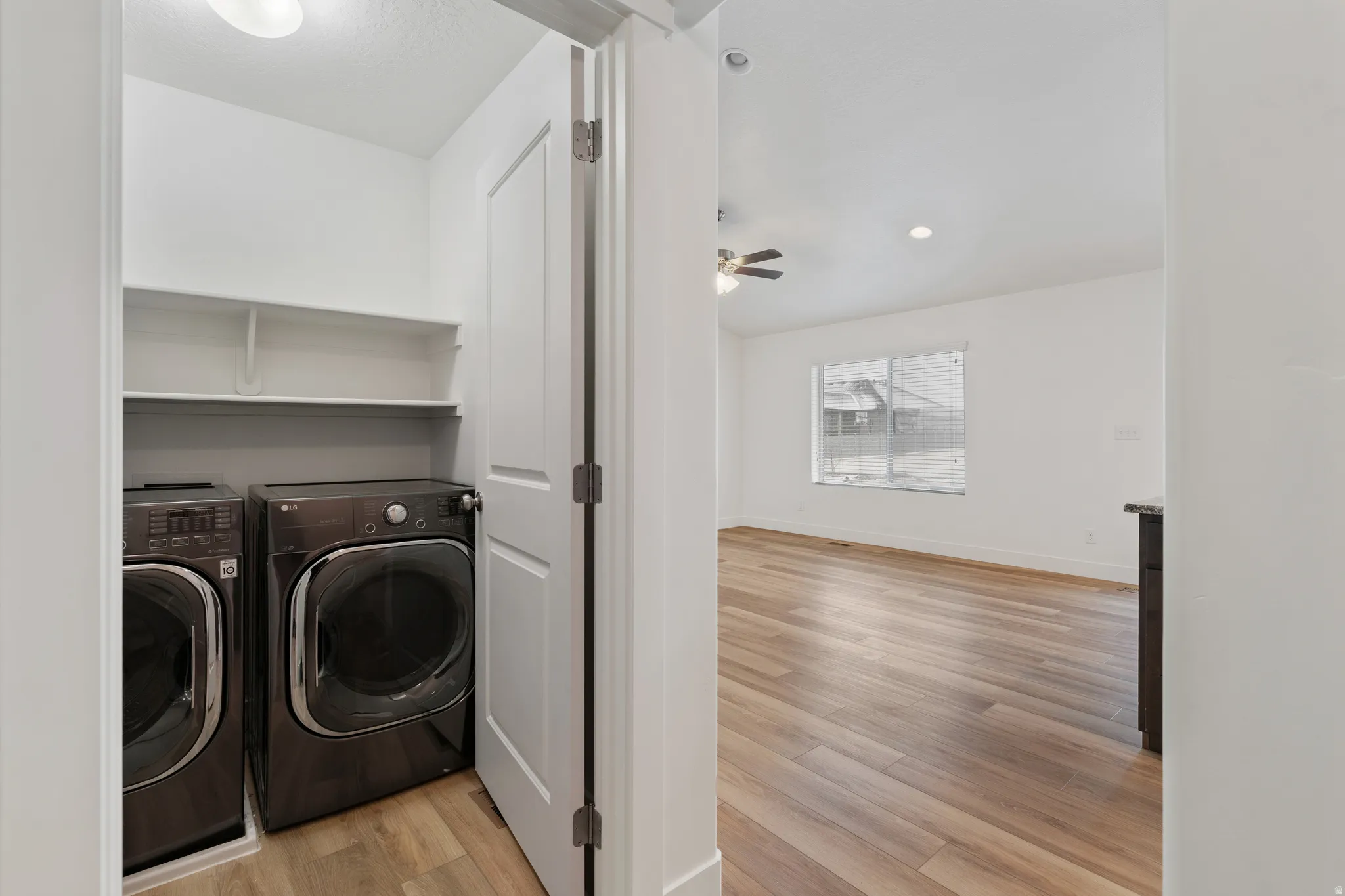 Laundry room with light wood-style flooring, washer and dryer, and a ceiling fan