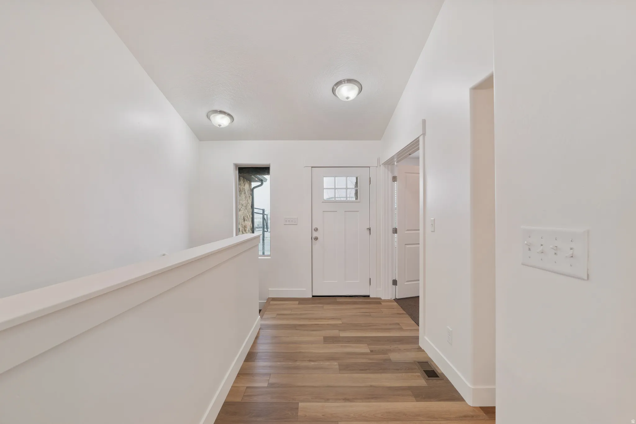 Corridor with light wood-style floors and baseboards