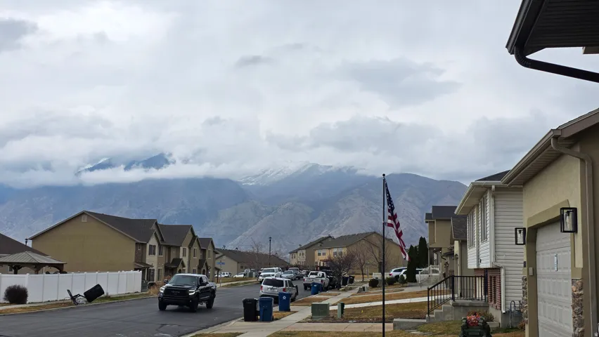View of asphalt street featuring a residential view, a mountain view, sidewalks, and curbs