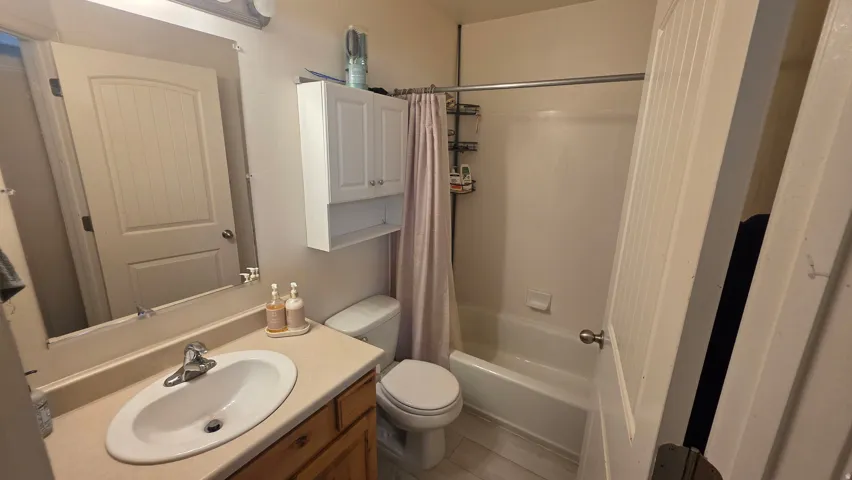 Full bathroom featuring vanity, shower / tub combo with curtain, and light tile patterned floors