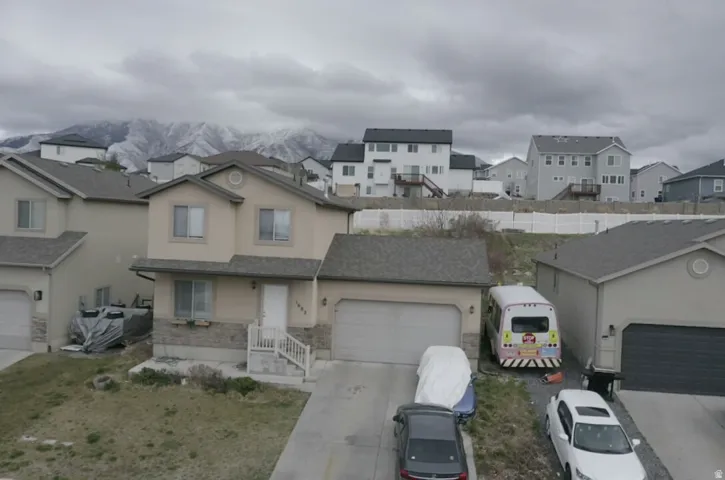 Traditional-style home featuring a residential view, stucco siding, concrete driveway, an attached garage, and stone siding