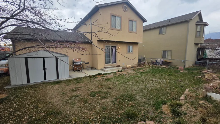 Rear view of property with stucco siding, a shed, a patio, a fenced backyard, and entry steps