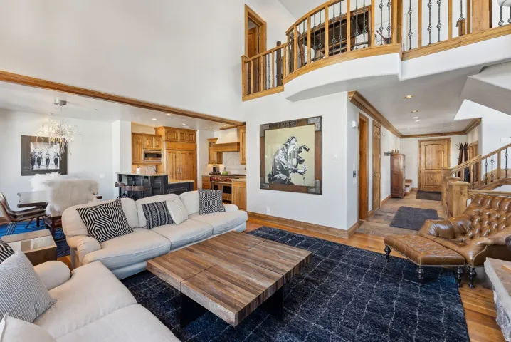 Living room featuring dark wood-style floors, hanging lights, and a high ceiling