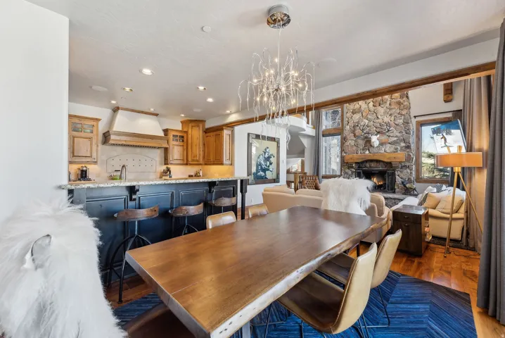 Dining room with dark wood finished floors, hanging lights, and a fireplace