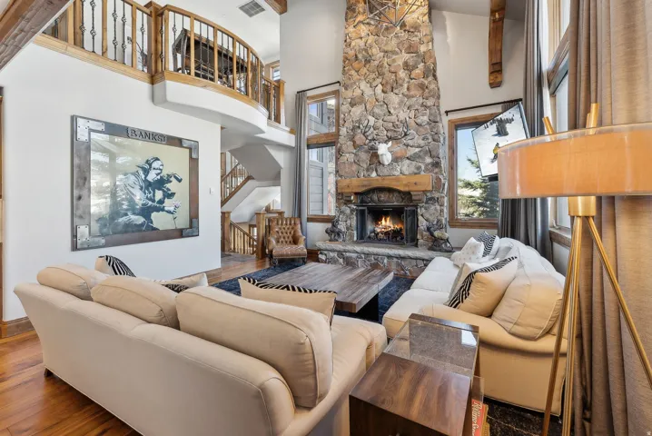 Living area featuring a stone fireplace, a high ceiling, and wood finished floors