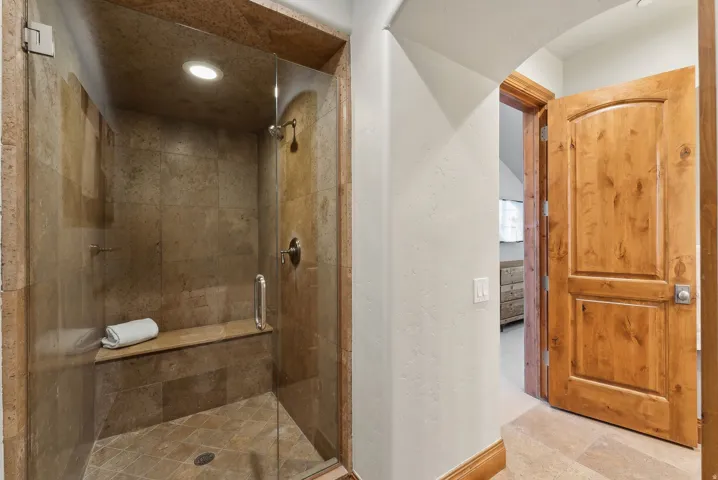 Bathroom with a stall shower, recessed lighting, and a textured wall